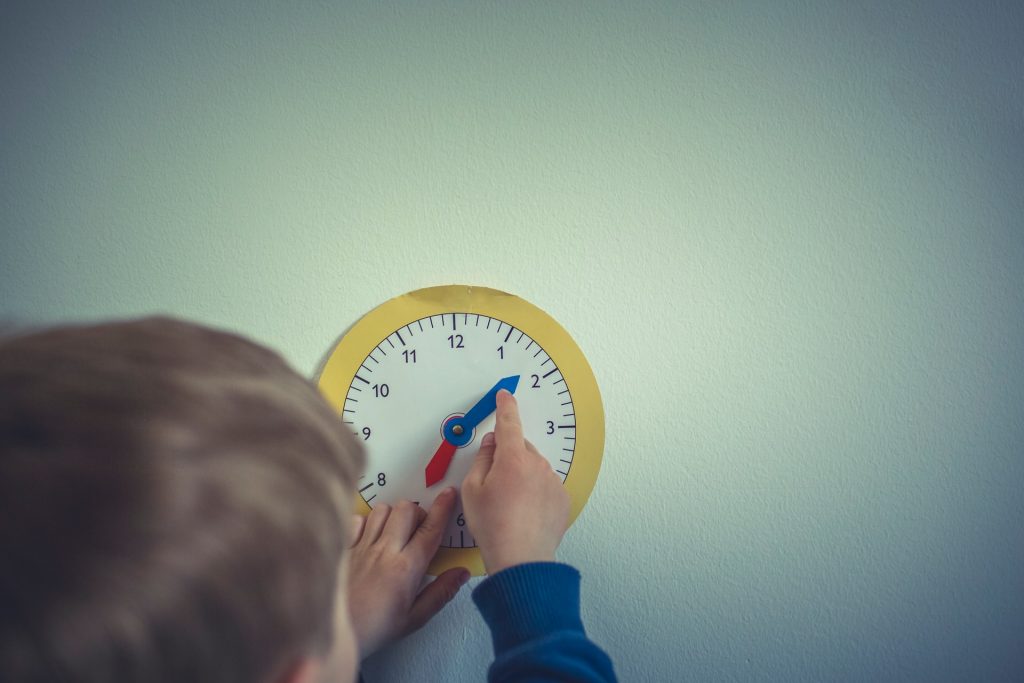 Kind verstellt die Zeiger einer Uhr